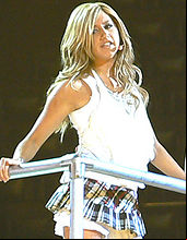 a young blonde haired female on a stage sings into a microphone